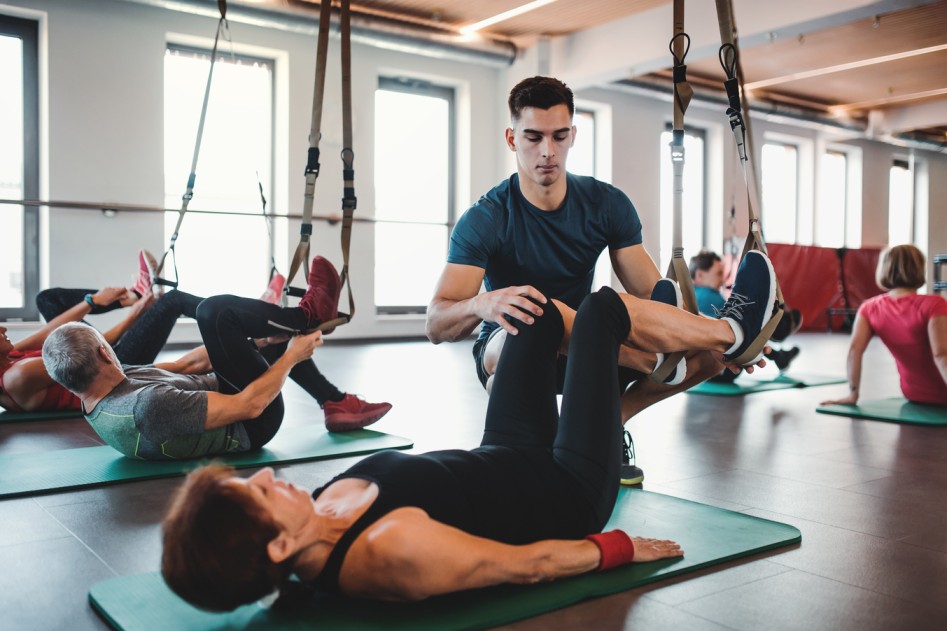 Interior of a premium Pilates Studio Las Vegas with reformer machines and a personal trainer guiding a client.