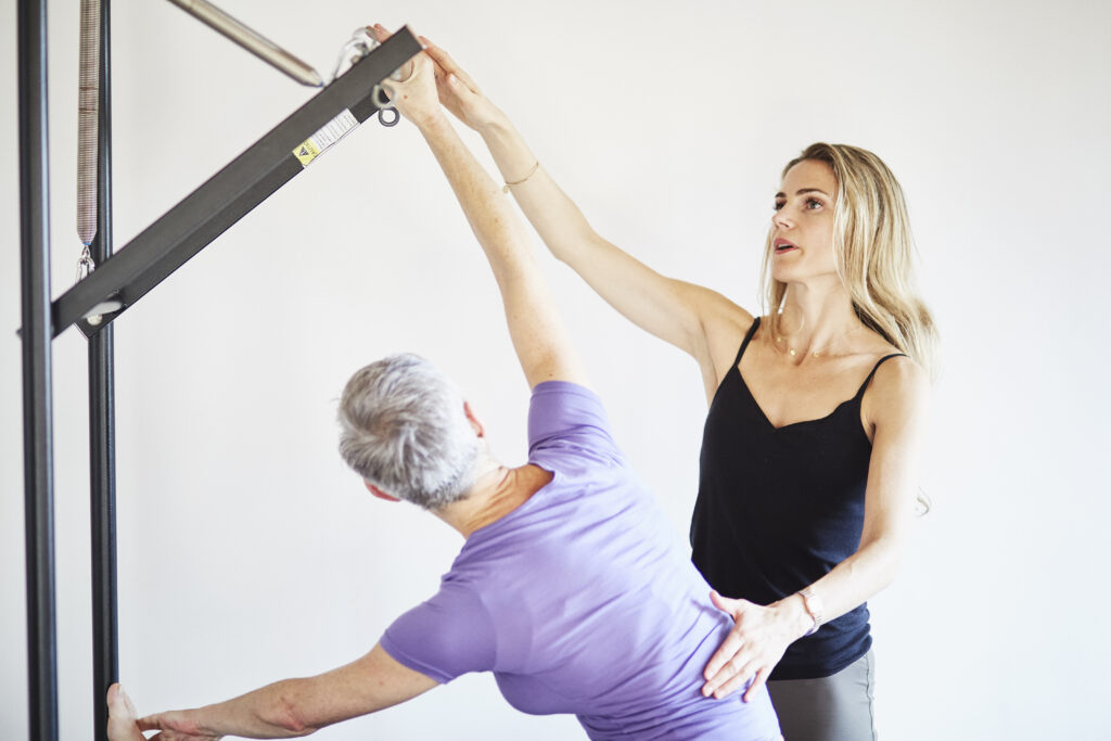 First-time student in a Pilates Vegas class learning reformer basics with instructor guidance.